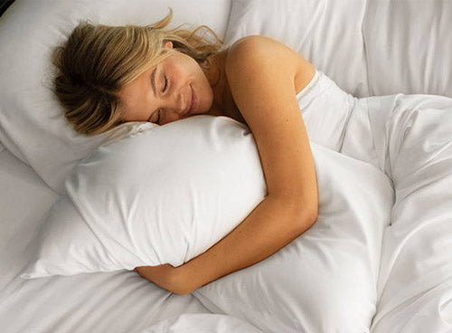 woman lying on a bed with white sheets