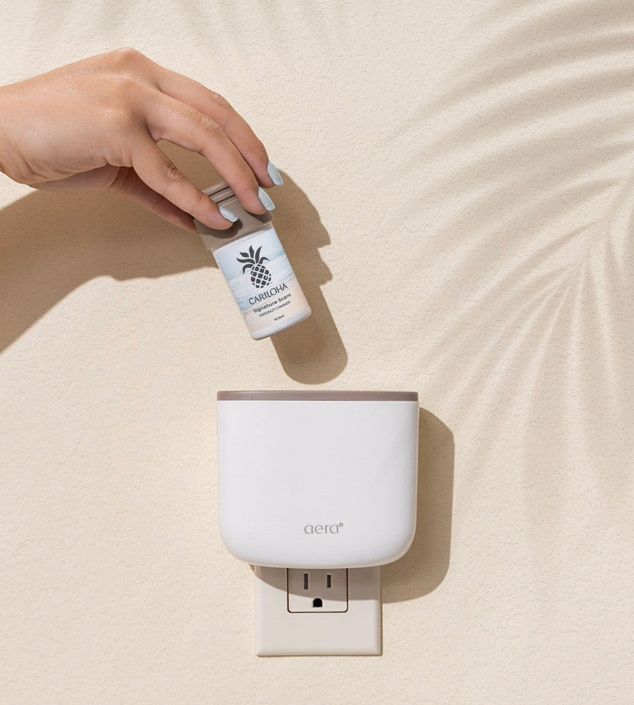 a hand putting a scent cartridge into an aera scent diffuser