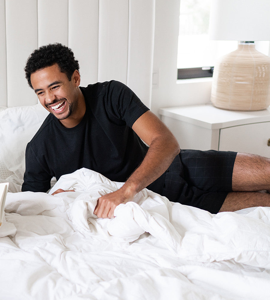 model lying on a bed wearing woven black shorts~Plaid Black