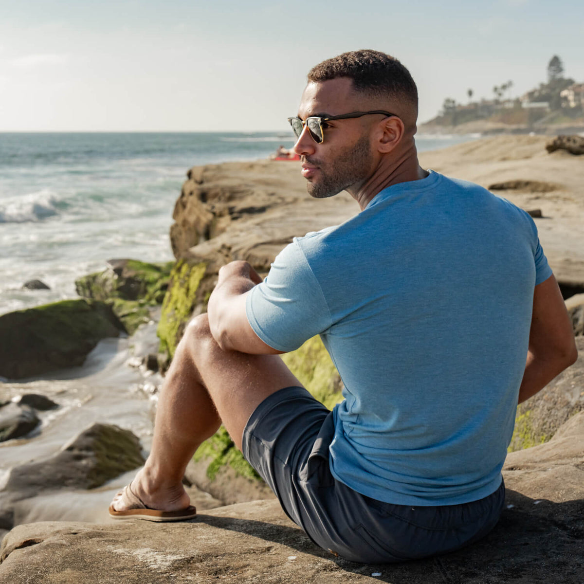 a man wearing a blue cariloha t-shirt sitting by the ocean
