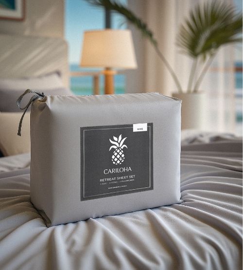 Cariloha Retreat Sheet Set wrapped in branded packaging on a bed with a coastal resort view in the background