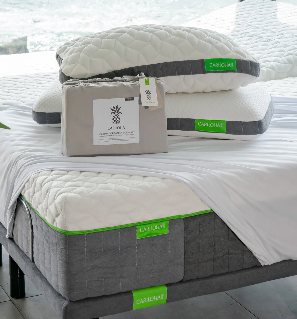 Cariloha sheet and pillow set displayed on a bed, with the mattress base, white quilted mattress topper, two white pillows, and a branded storage box in the foreground.