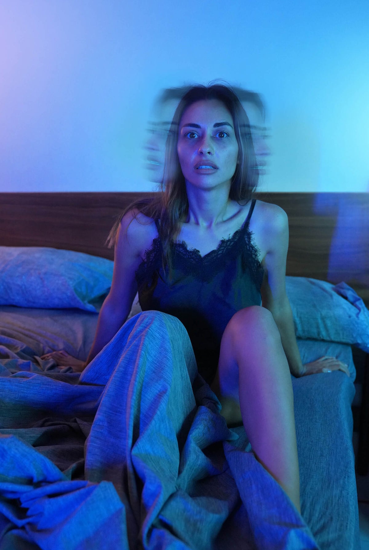 a woman sitting in bed scared