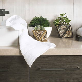 White Cariloha bamboo hand towel draped over a bathroom counter beside potted succulents