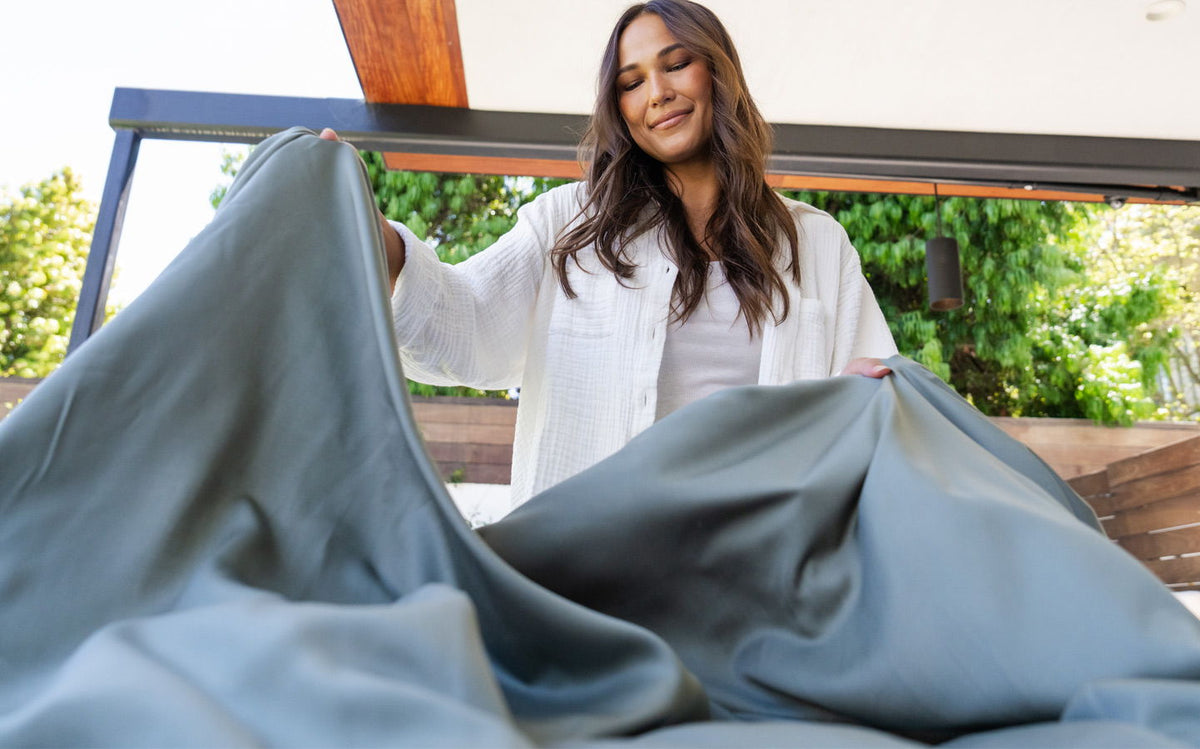 Woman making a bed with bamboo sheets